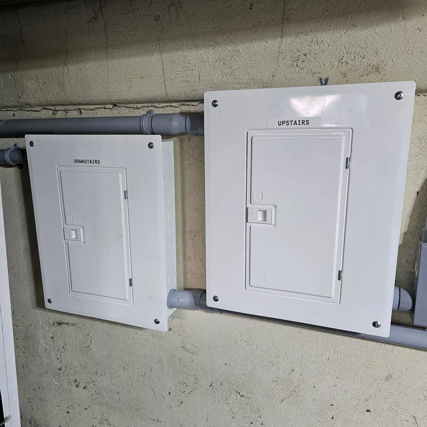Two labelled electrical panels for the upstairs and downstairs units